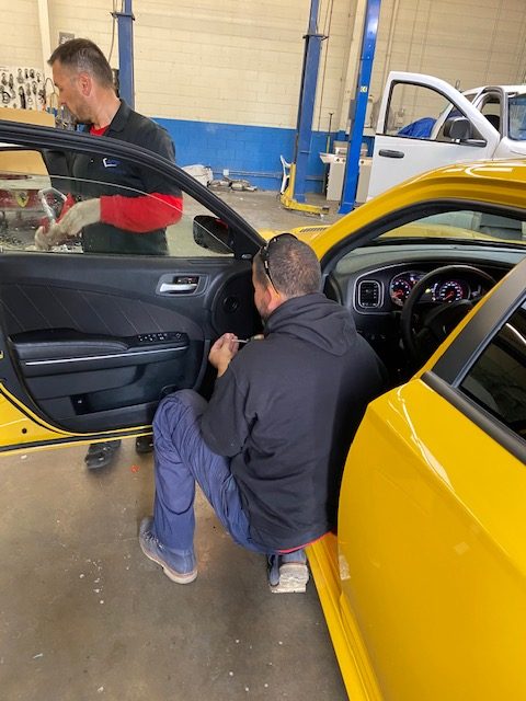 Auto Glass Force technicians working on a yellow vehicle
