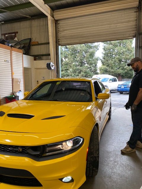 Yellow Dodge inside Auto Glass Force shop